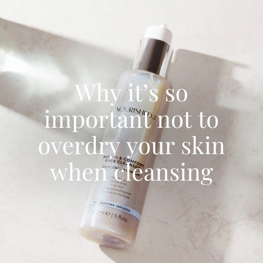 A Nourished3 facial cleanser bottle placed on a light stone surface, illuminated by natural light and casting a soft shadow.